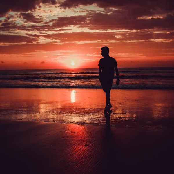 Person meditating peacefully outdoors during a beautiful sunset.