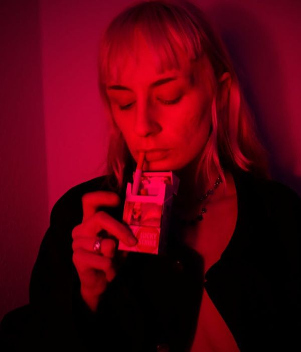 Woman in a calm yoga posture in a dark room with purple light.